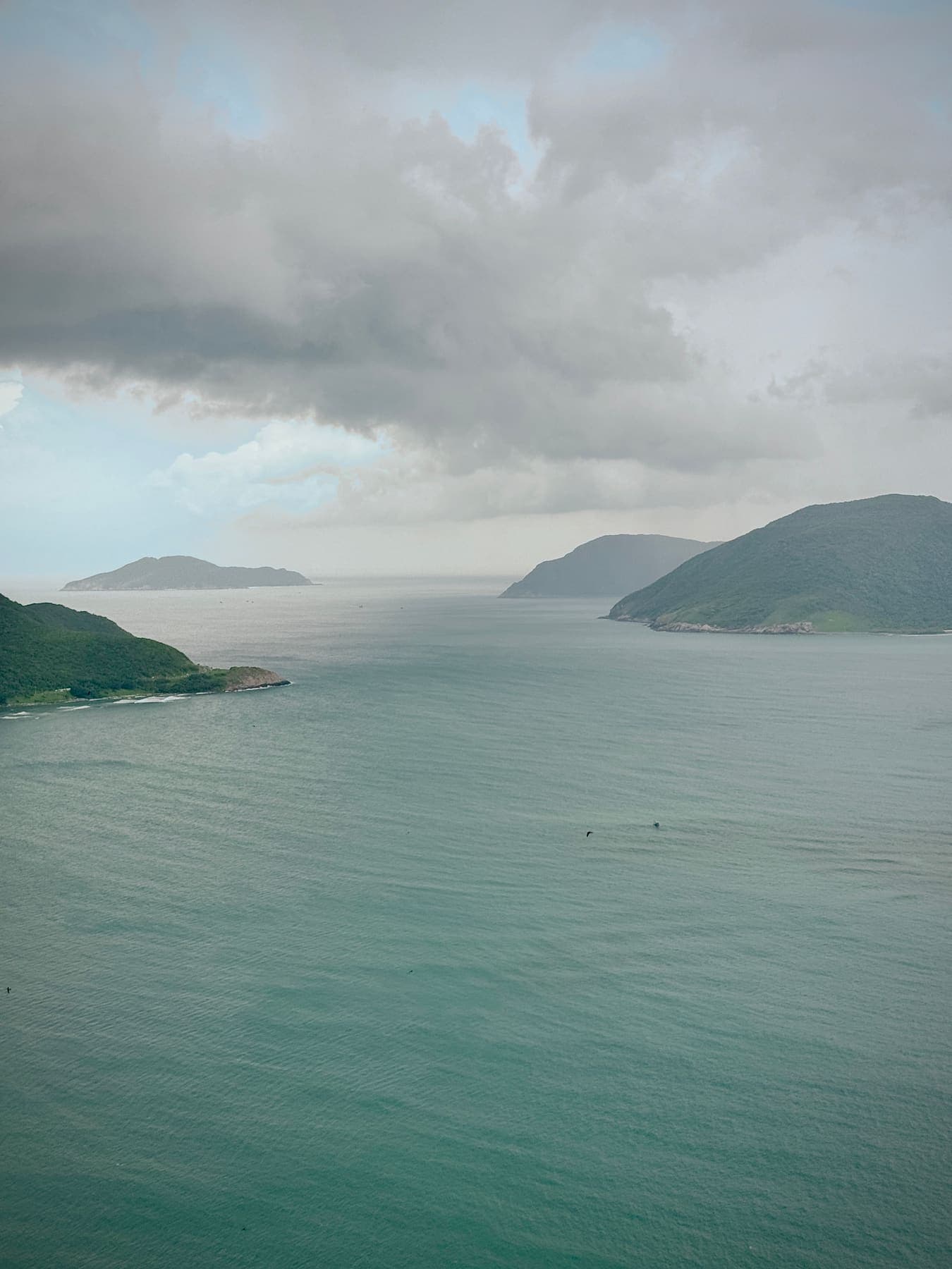 Green islands in a calm bay under heavy grey clouds