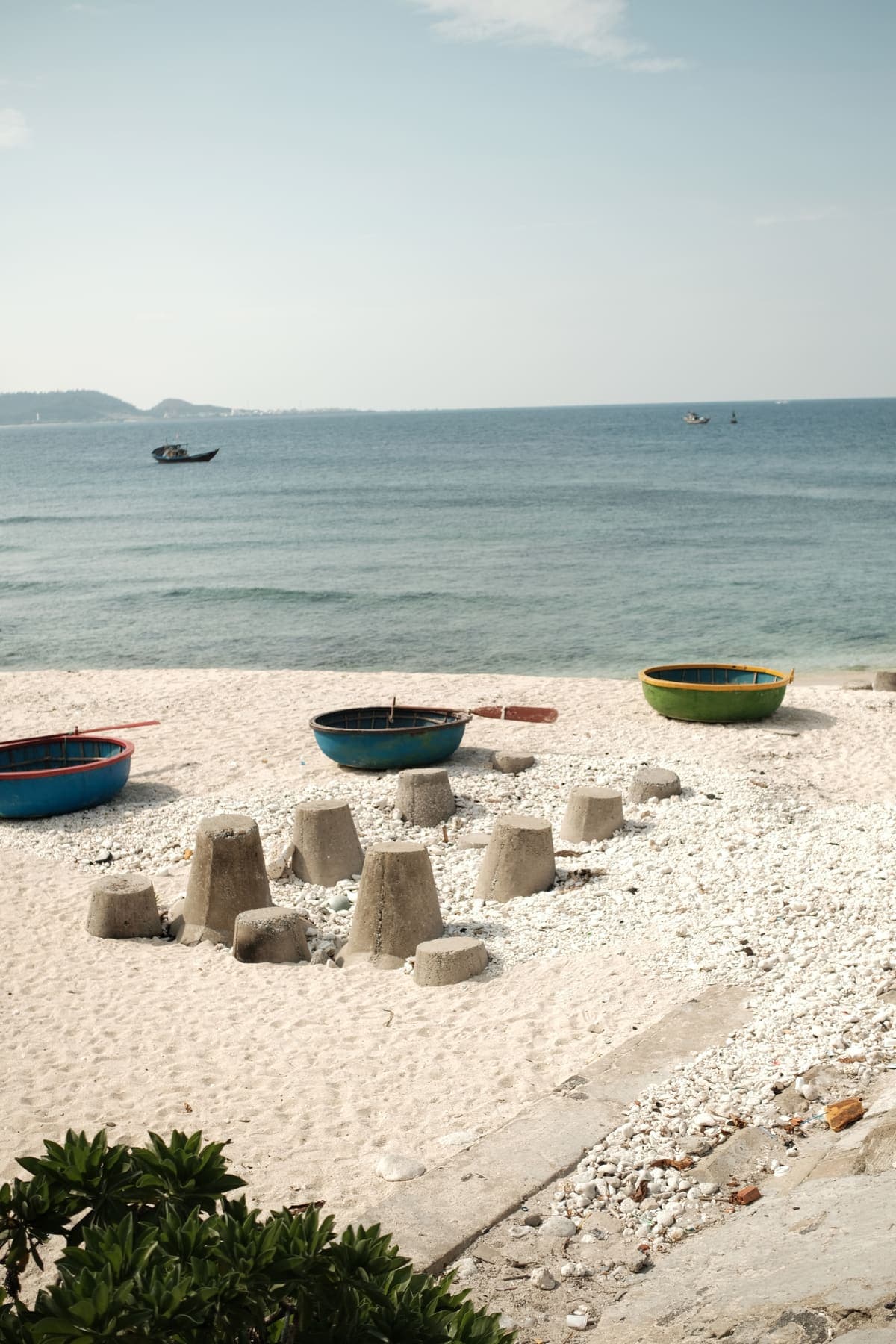 Round basket boats and concrete blocks on a white sand beach