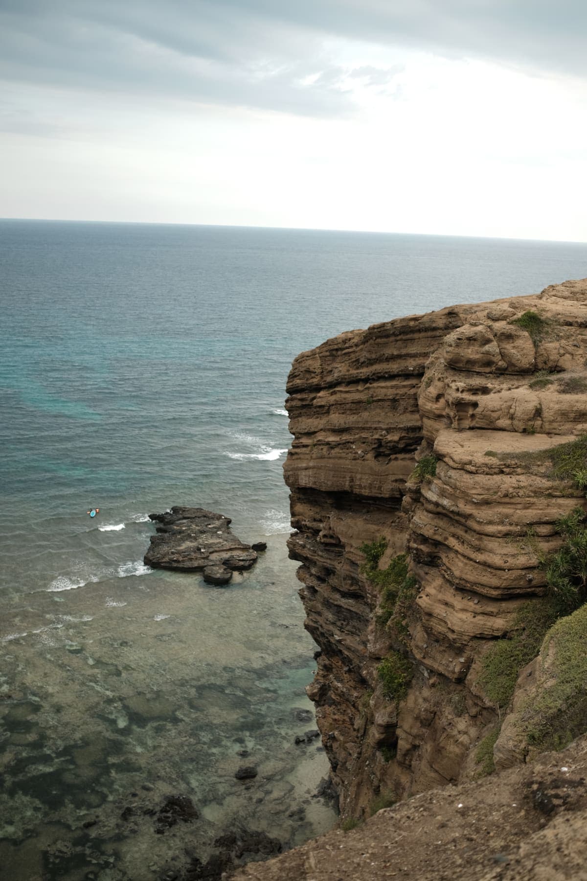 Layered volcanic cliffs dropping into shallow turquoise water