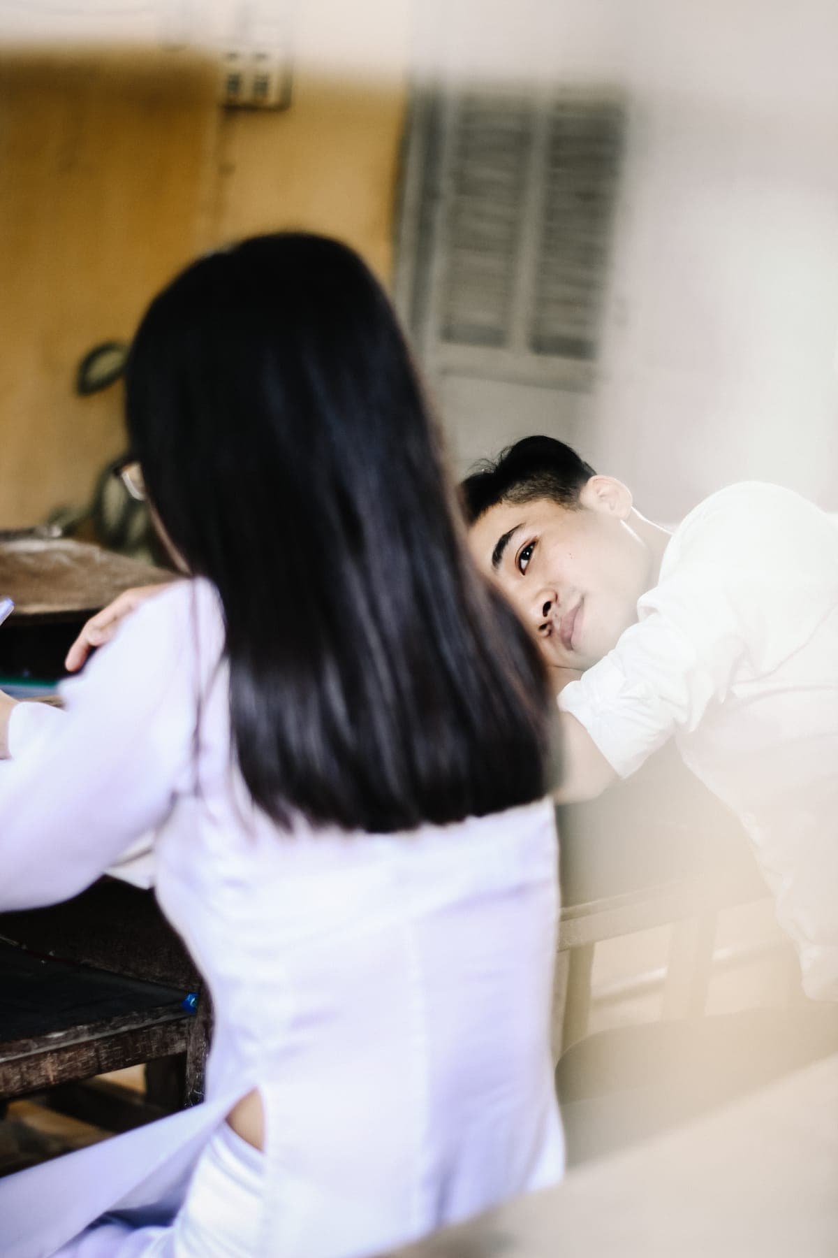 A boy smiling at a girl in an áo dài, seen over her shoulder