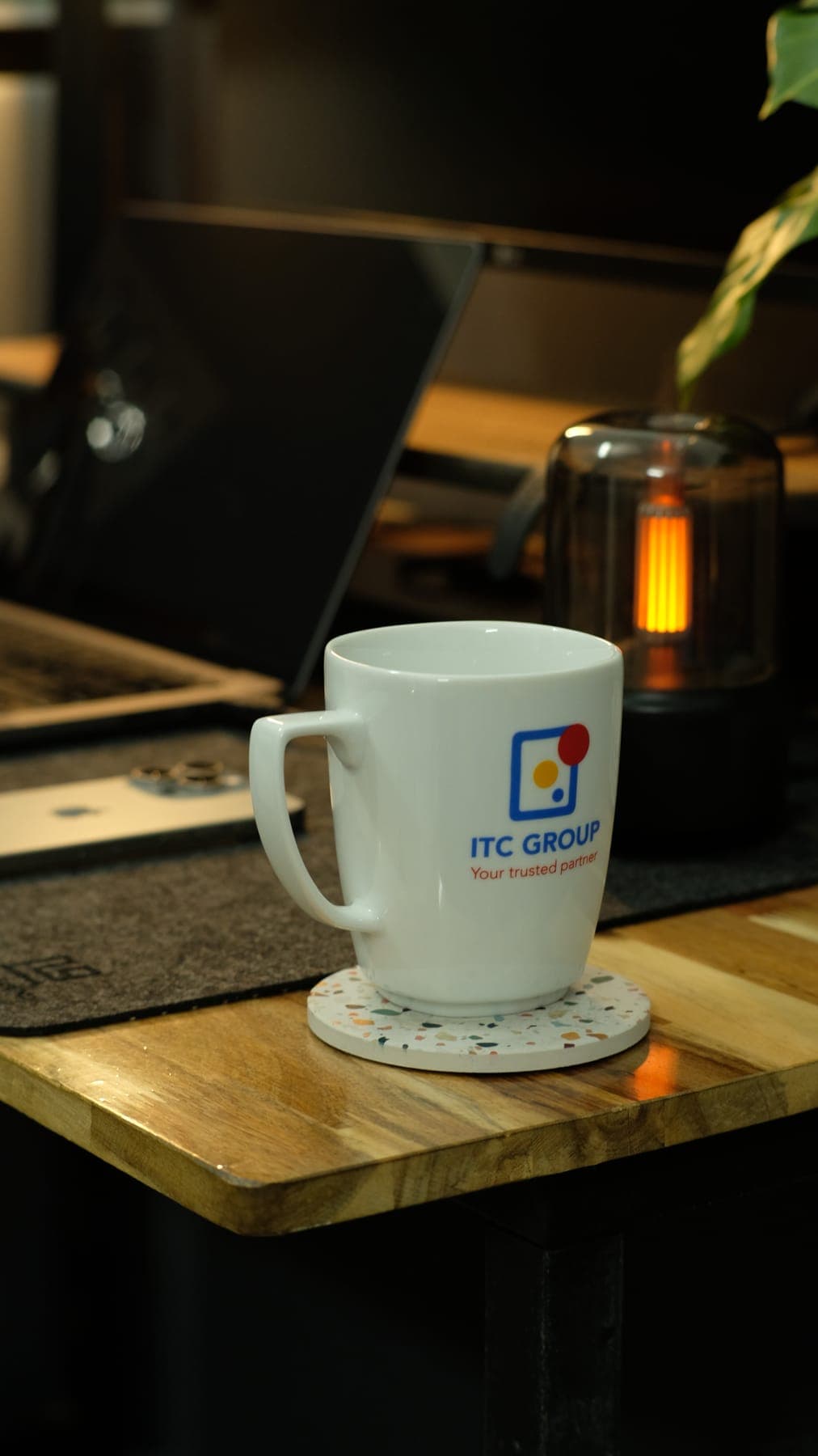 A white mug on a coaster with the lantern glowing behind it